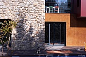 Modern facade in rustic stone and glass with large coloured planes