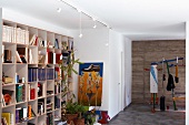Heller Raum mit buntem Fitnessgerät, moderner Malerei und lebendiger Bücherwand