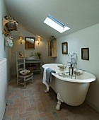 Freistehende, antike Badewanne unter der Dachschräge in einfachem Badezimmer eines nordfranzösischen Landhauses