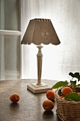 Apricots on table and in wicker basket in front of county-house-style table lamp