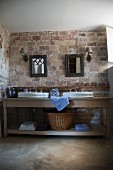 Washstand with twin basins against rustic brick wall in bathroom of Provençal country house