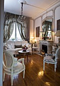 Elegant room with fireplace, large mirror on chimney breast, Baroque furniture in natural shades and glossy parquet floor