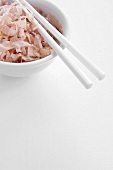Finely chopped onion and chopsticks in a white bowl