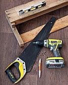 Saw and cordless drill next to home-made, wall-mounted shelf and spirit level