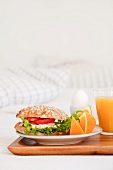 A breakfast of fresh orange juice, egg and a ham sandwich