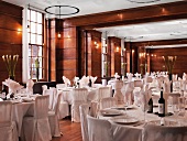 Tables set in white in restaurant with wood-panelled walls