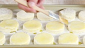 Buttermilk biscuits being brushed with egg yolk