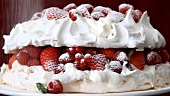 Berry pavlova being dusted with icing sugar (close-up)