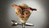 An ice cream sundae garnished with fried bacon skewer