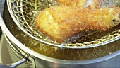 A chicken leg being breaded and fried