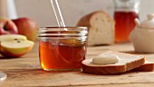 Honey being spread onto a slice of bread with a plastic spoon