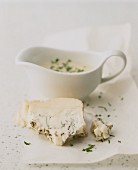 A slice of blue cheese and cheese sauce in a gravy boat