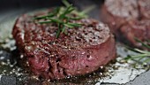 Entrecote with rosemary being fried in a pan and sprinkled with pepper