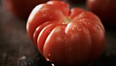A beef tomato with droplets of water
