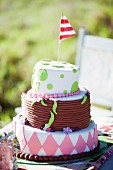 Decorated, tiered celebration cake with red and white flag