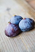 Three fresh figs on a wooden surface