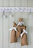 Advent calendar made from small, numbered linen bags hung on wooden rack