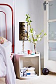 Flowering branch and table lamp on white, retro bedside cabinet next to open, latticed French window