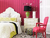 Romantic bedroom with Baroque-style furniture; flowering branch of magnolia on chest of drawers against striped wallpaper