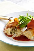 Filled filo pastry parcels with tomato sauce and rocket on a white plate