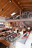 Lounge area in mixture of styles in spacious living room with mezzanine and view of exposed roof structure