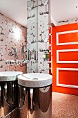 Marble sink with chrome base against mirrored wall with swan-shaped tap fitting; bright orange door with white mouldings in background