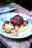 Veal cheeks on a bed of mashed potatoes with mushrooms and sauce