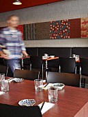 Zwischen gedeckten Esstischen laufender Kellner in japanischem Restaurant