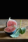 A halved figs with a fig leaf on a wooden surface