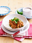 Butter chicken (Indian chicken curry) on a bed of rice with raita