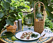 Feigen mit Ricotta auf einem Teller und Weißwein auf einem Gartentisch