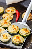 Grilled courgette slices with feta on a baking tray and a spatula