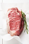 Two slice of entrecôte with rosemary on parchment paper