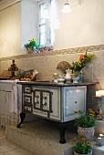 Vintage kitchen stove on platform against half-height wall tiling in simple, country house kitchen