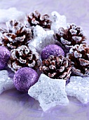Christmas arrangement of purple baubles, stars and pine cones