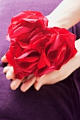 Ein Herz aus Rosenblütenblätter in Frauenhänden