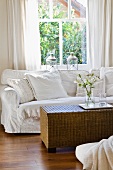 White sofa and wicker table in front of window