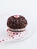 A cupcake decorated with butter cream and chocolate sprinkles