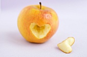 An apple with a heart-shape cut out of it