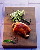 Pork knuckle with salad and spices on a chopping board