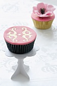 A cupcake with pink icing and golden decoration