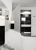 Schwarz weiße Wandlampen neben Doppelbett mit weisser Bettwäsche und Blick ins Bad ensuite