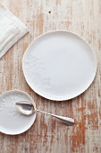 A white porcelain plate and an underplate with a silver spoon