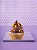 A chocolate cupcake against a purple background