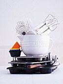 A hand mixer, a whisk, a mixing bowl, muffin cases and a muffin tin
