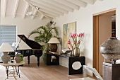 Music room with open, black grand piano; three vases of pink flowers on black sideboard against wall