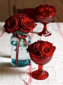 Red roses in glasses and jar