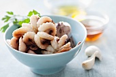 A bowl of raw octopus with garlic and vinegar in the background