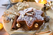 A star-shaped spiced cake with almonds and Christmas baubles on a Christmas angel plate