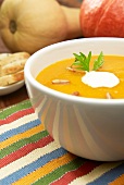 Pumpkin soup with a dollop of cream and roasted pine nuts